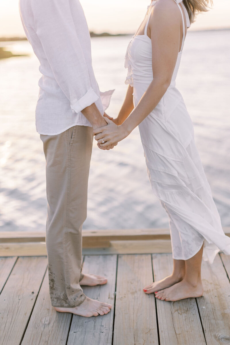 Couple stands on a dock holding hands at Assateague island