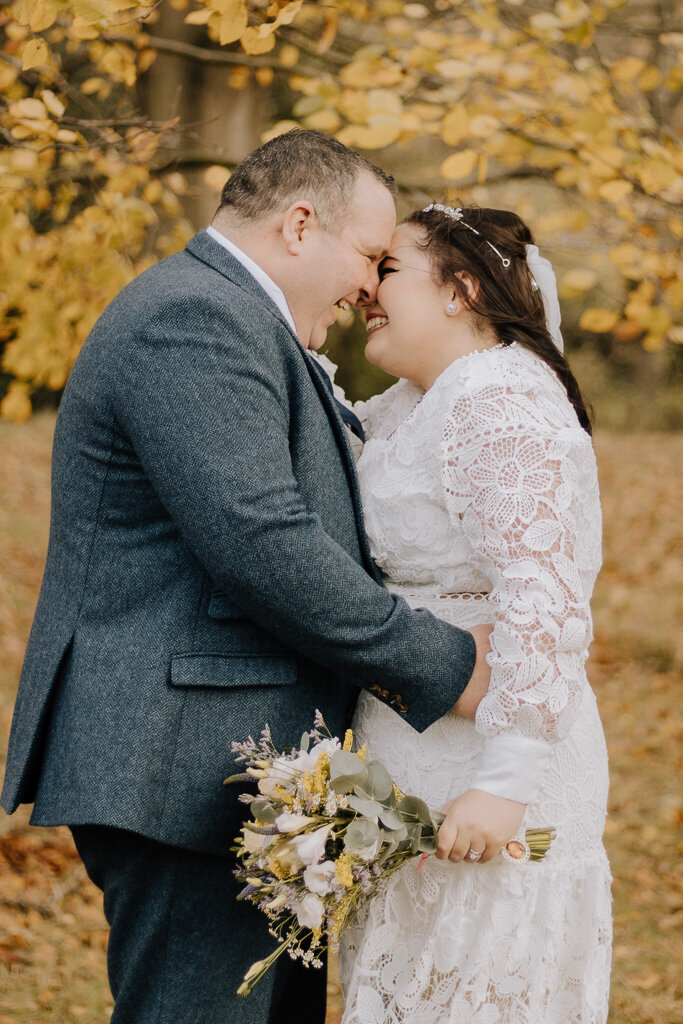 Bride and groom sharing a kiss in the autumn leaves at Chatsworth House