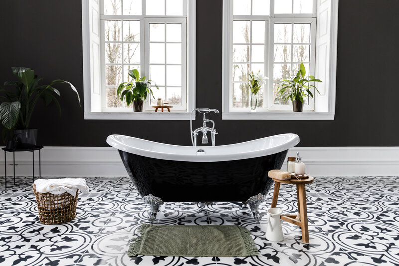 Modern black and white bathroom design with mosaic floor tile and black stand alone bath tub.