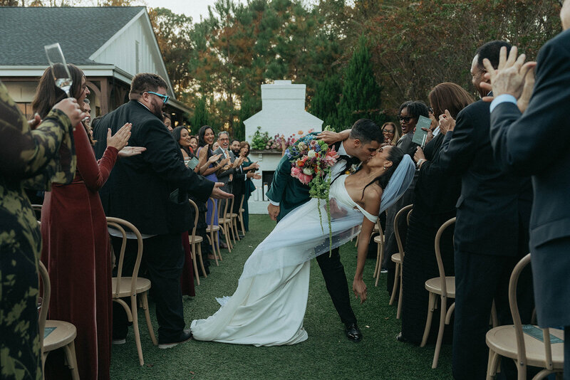 couple kissing down the aisle on their wedding day, captured by Elsie Goodman, an NYC wedding, engagement and couples photographer