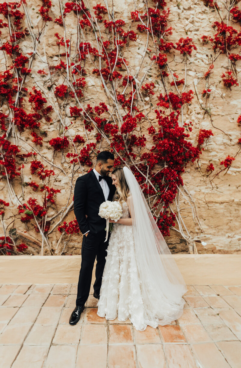 couple embracing in front of bougainvillea