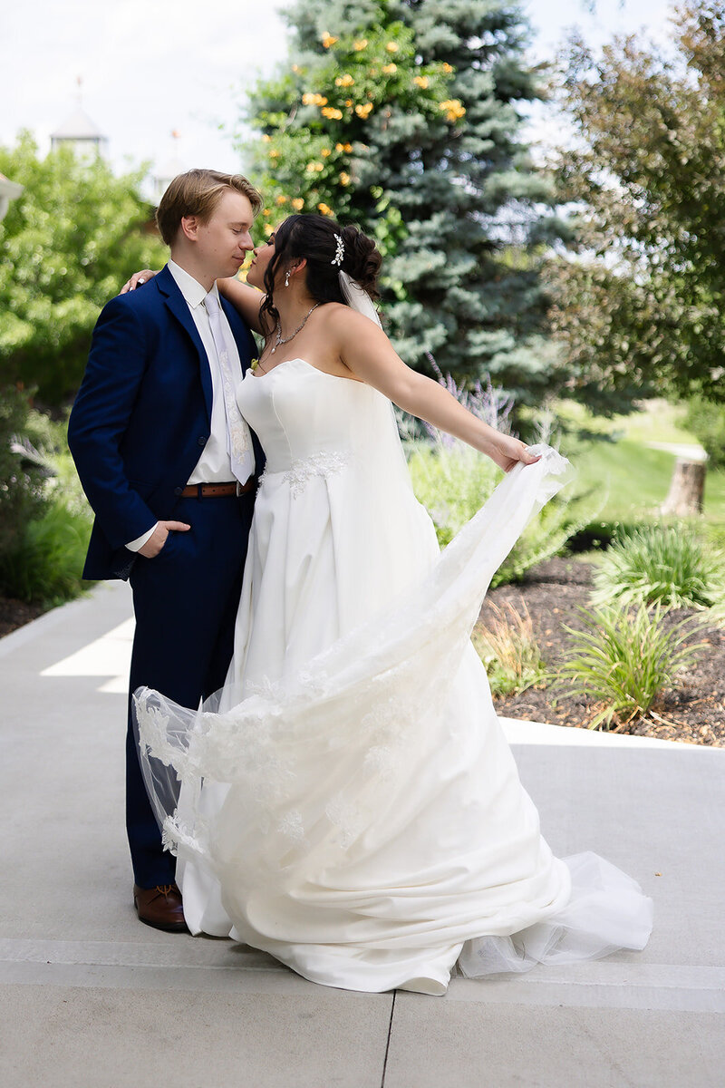 bride and groom embracing while standing in a field
