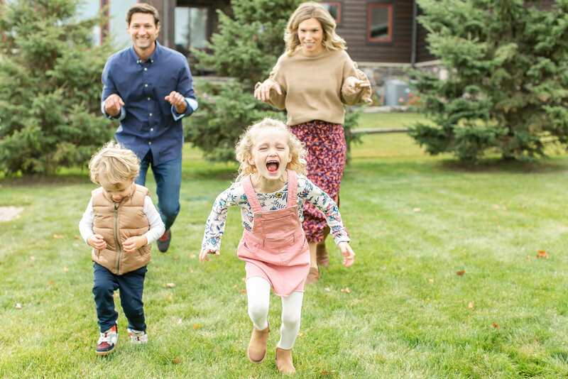 A little boy and a little girl running toward the camera away from their parents in the background.