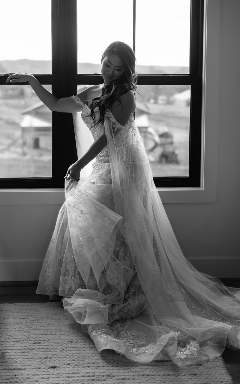 Bride poses, B&W, in front of the window.
