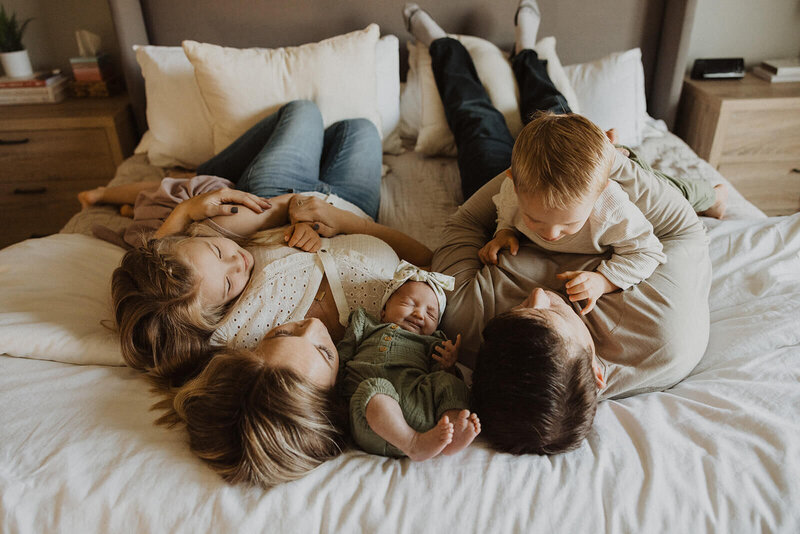 Family plays and cuddles together on parents' bed