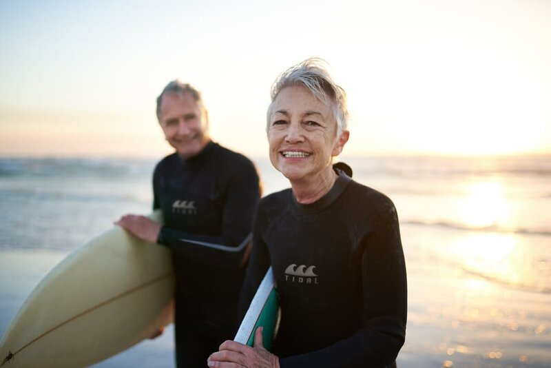 man and woman coming out of the water after surfing