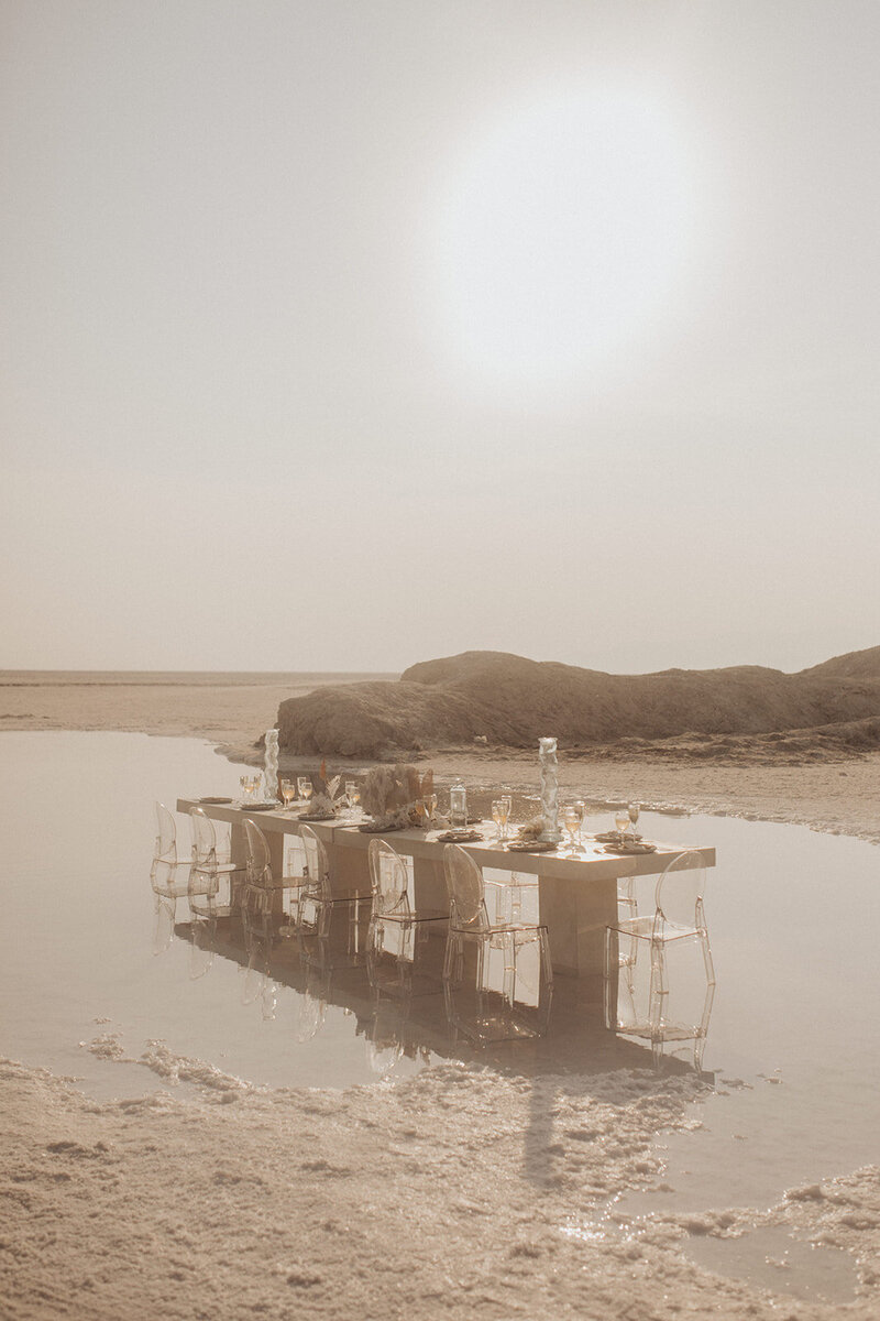 A serene table setup for a fine dining experience on a desert shore.