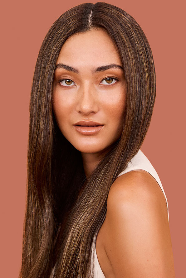 Woman with smooth, straight brunette hair and subtle highlights styled by an expert Sydney hairdresser.