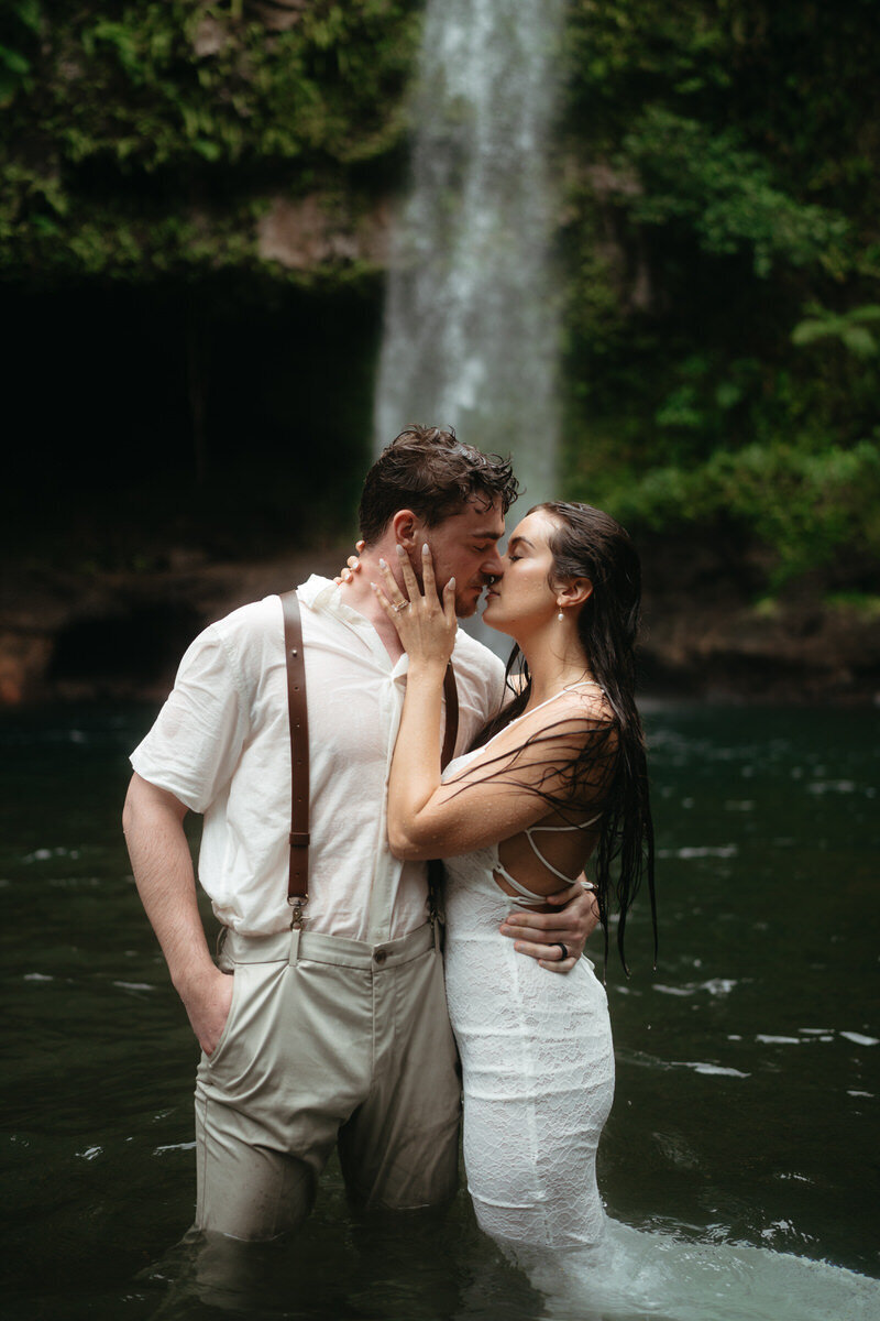 Elopement Photo Ideas | Eloping couple kisses each other standing  knee deep in the water with a huge waterfall behind them