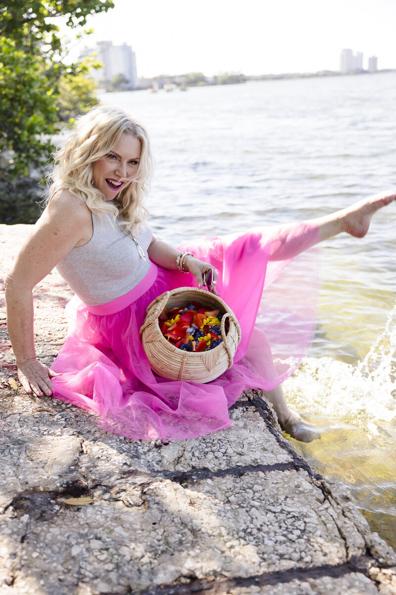 heather sitting by water with flower petals