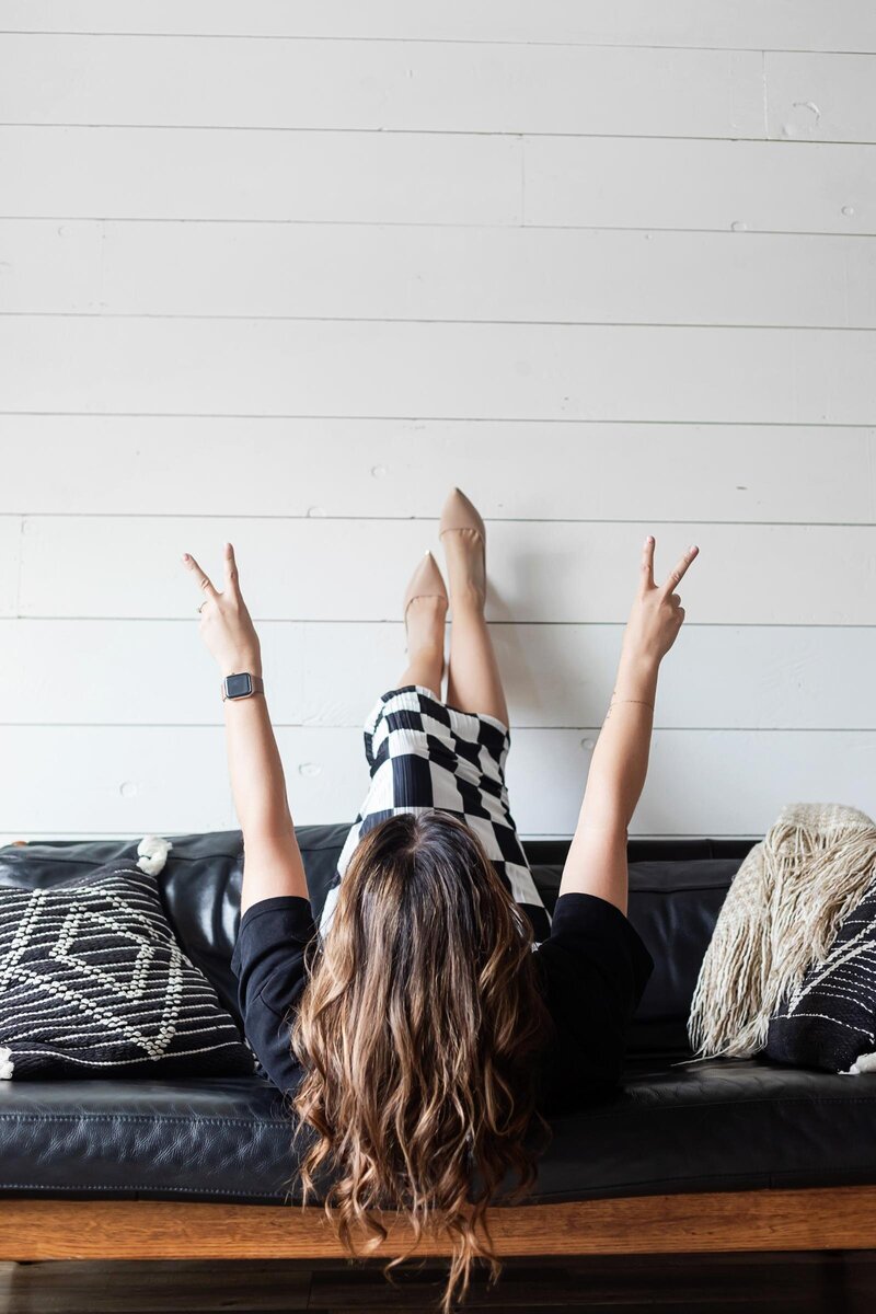 girl on couch throwing up the peace sign