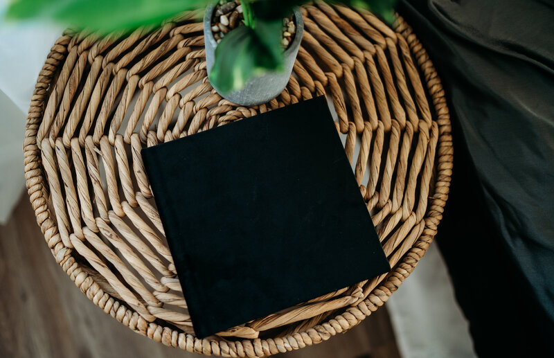 Details of a closed mini photo album  laying on a wicker side table
