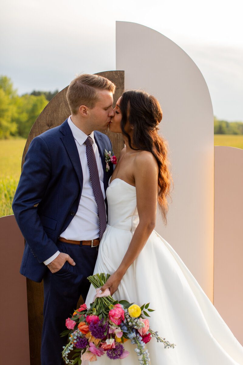 Groom is behind bride and pulls her close as they giggle at each other