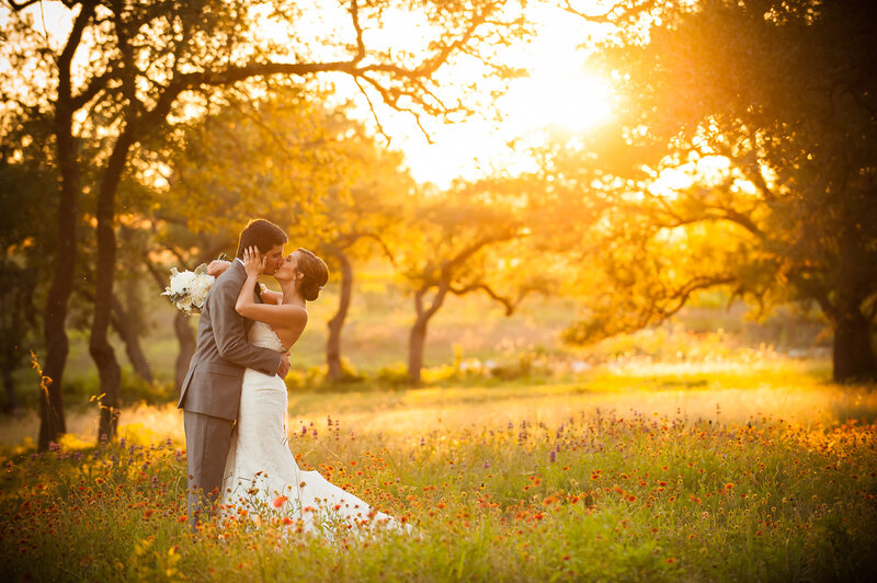 couple kissing in a field at sunset at Dripping Springs wedding venue