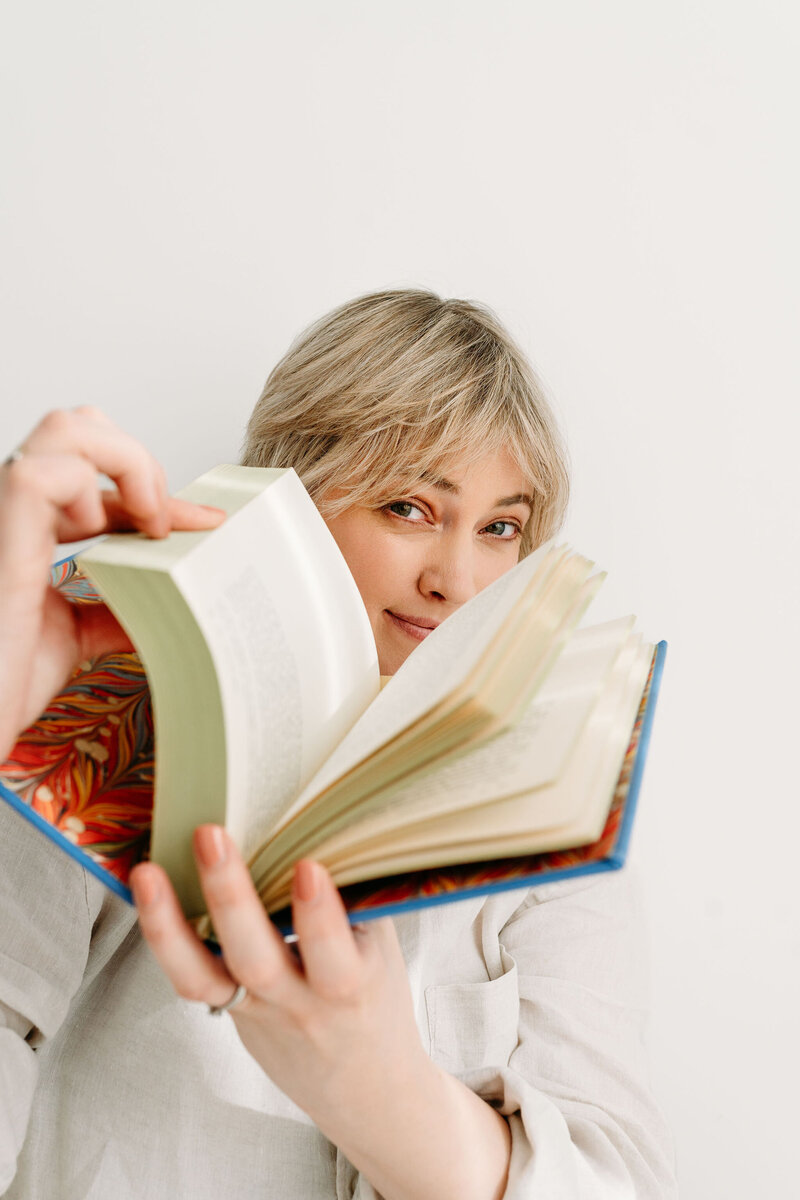 Rosanne Sarah, zelfstandig redacteur en schrijfcoach voor romanschrijvers, kijkt door een boek waarin ze aan het bladeren in de camera in. 