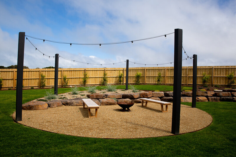 An outdoor space for entertaining with seating and fireplace surrounded by a rock wall