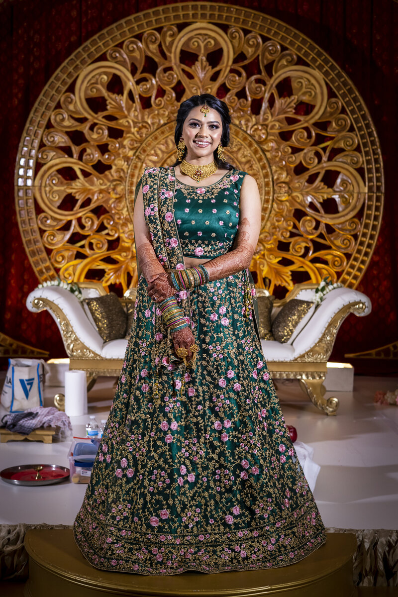 Indian bride standing in front of golden backdrop.