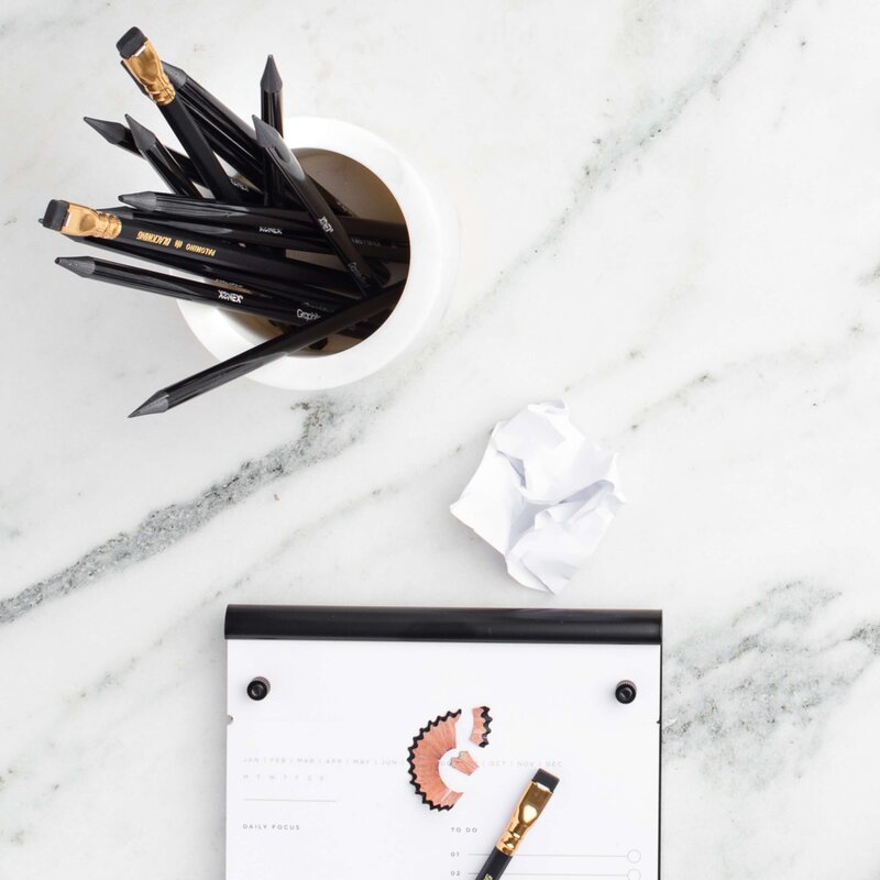 marble desk overlay with black wing tip pencils ined notepad and pencil shavings