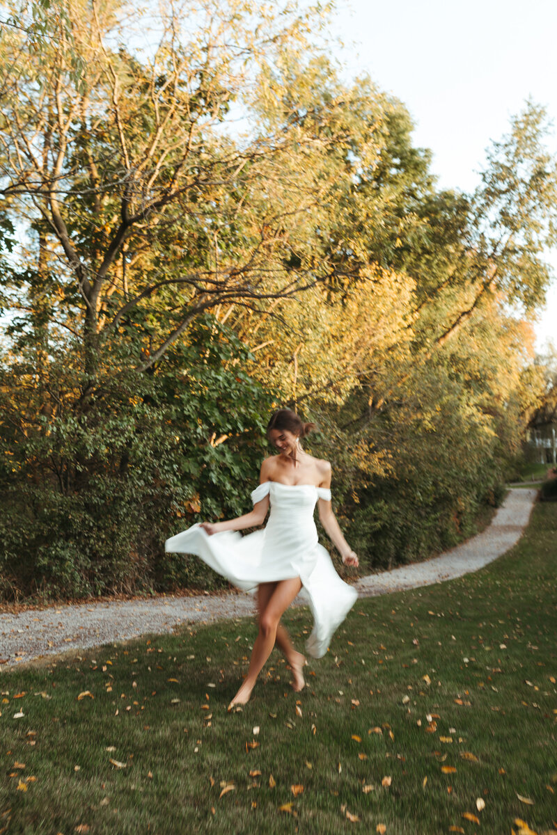 A bride frolics in her backyard among the trees