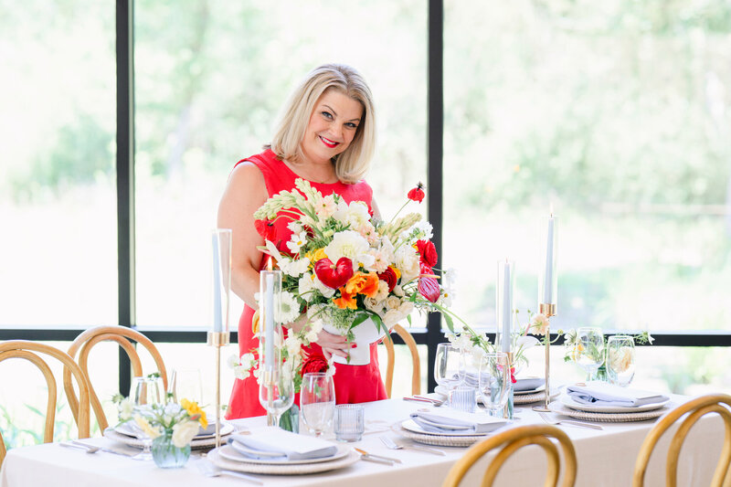 Austin wedding planner arranging a vibrant floral centerpiece at a styled reception table, showcasing joyful, thoughtful wedding planning.