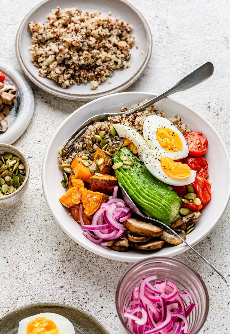 Nourishing fertility abundance bowl with quinoa, avocado, egg, sweet potato, tomatoes, and seeds — a vibrant, balanced meal to support male and female fertility and hormone health.