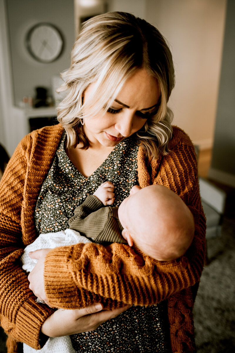 In home newborn session with mom holding baby wearing neutral colors