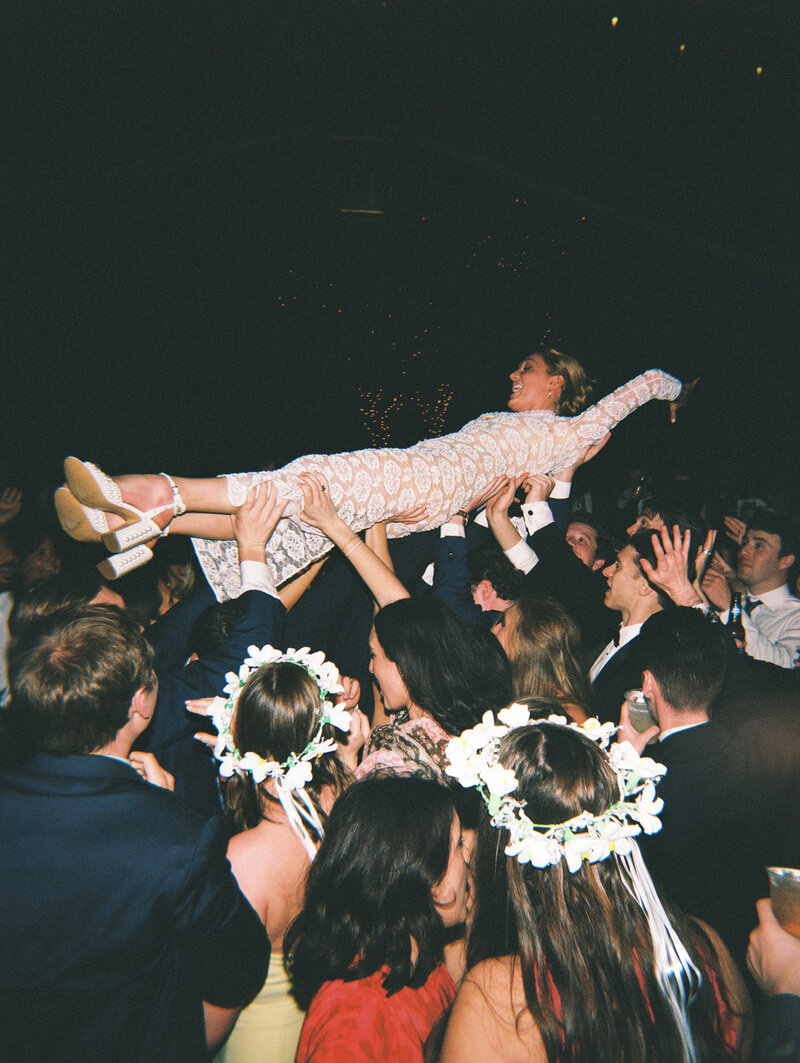 Flash film photo of wedding reception guests lifting bride into the air
