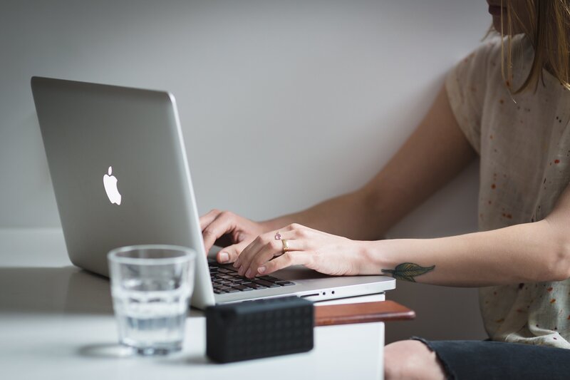 woman sitting at desk typing on laptop
