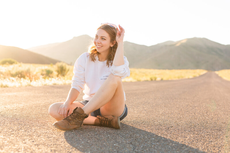 girl in white jeans laughing and looking at camera with idaho mountains behind her