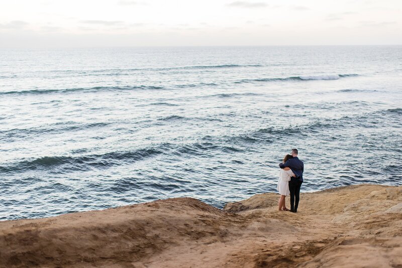 Couple embraces on a cliff.