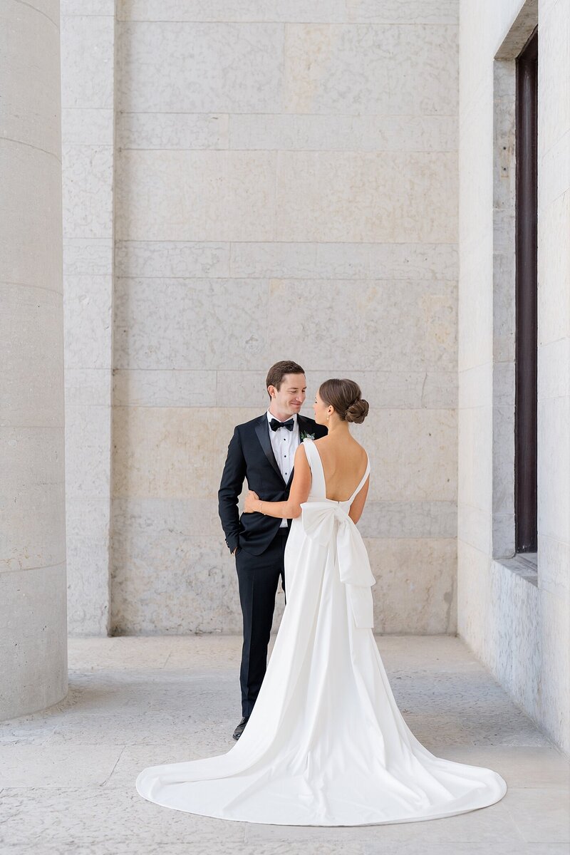 Columbus wedding photographer  photographs wedding photographer with a groom in a tux holding his hands in his pockets and smiling at his bride as she wraps her arms around him