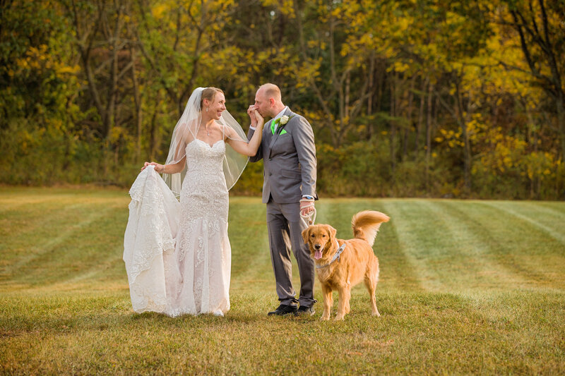Bride and groom walking with their dog at golden hour during a private backyard elopement, creating a warm and intimate moment.