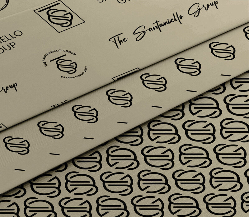The Santaniello Group logo and brand pattern displayed on high-end packaging material, showcasing a sophisticated and cohesive brand identity.