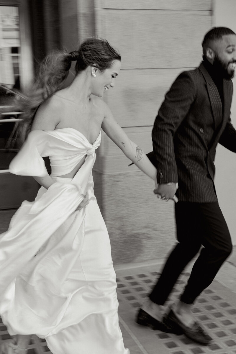 Black and white editorial engagement photo of a couple running hand in hand, photographed by Greenville wedding photographer Dani Lacey Photographs.