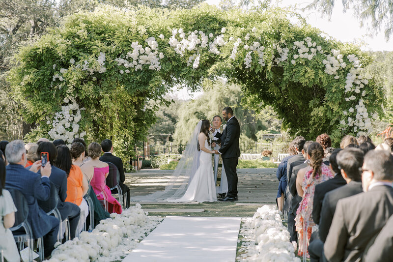 outdoor wedding ceremony under luxury floral arch