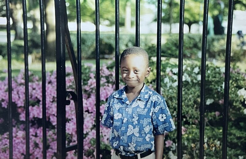 little boy smiling by the white house