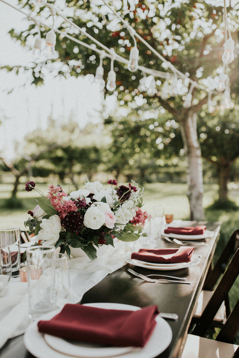 A table set with plates, flowers, and drinks in a cherry orchard wedding venue