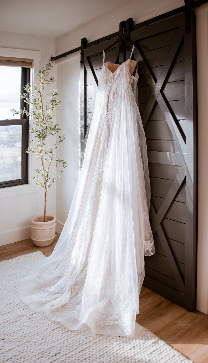 Wedding dress handing from the black barn doors with sunbeams shooting across it. In the bridal suite, of course.