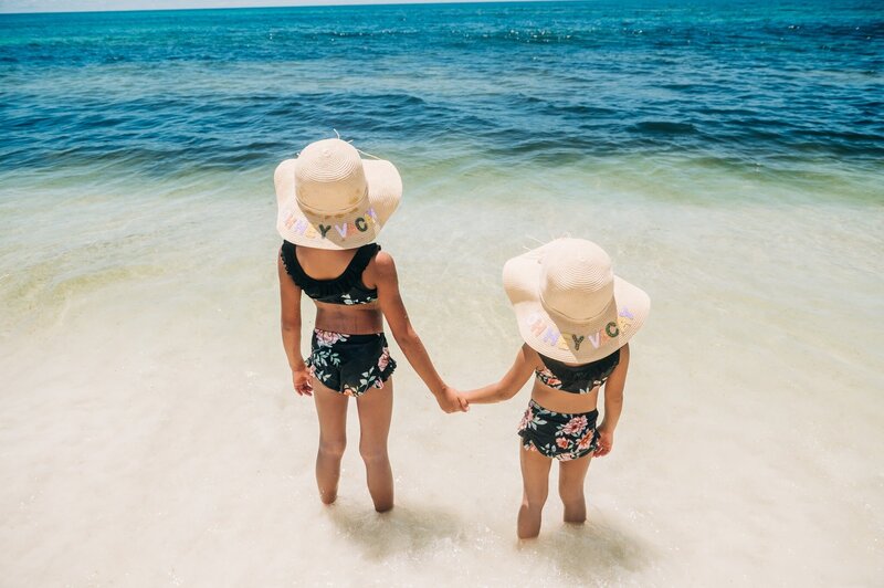 girls with hats facing water at Pensacola Beach