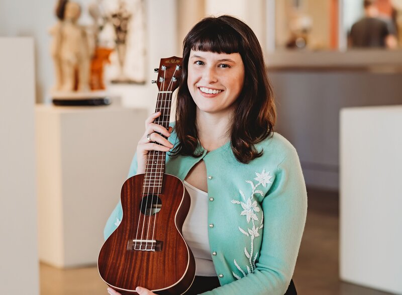 Branding photograph of young woman in mint sweater holding a ukelele