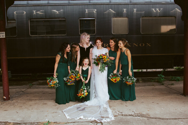 bride and women smiling in front of train