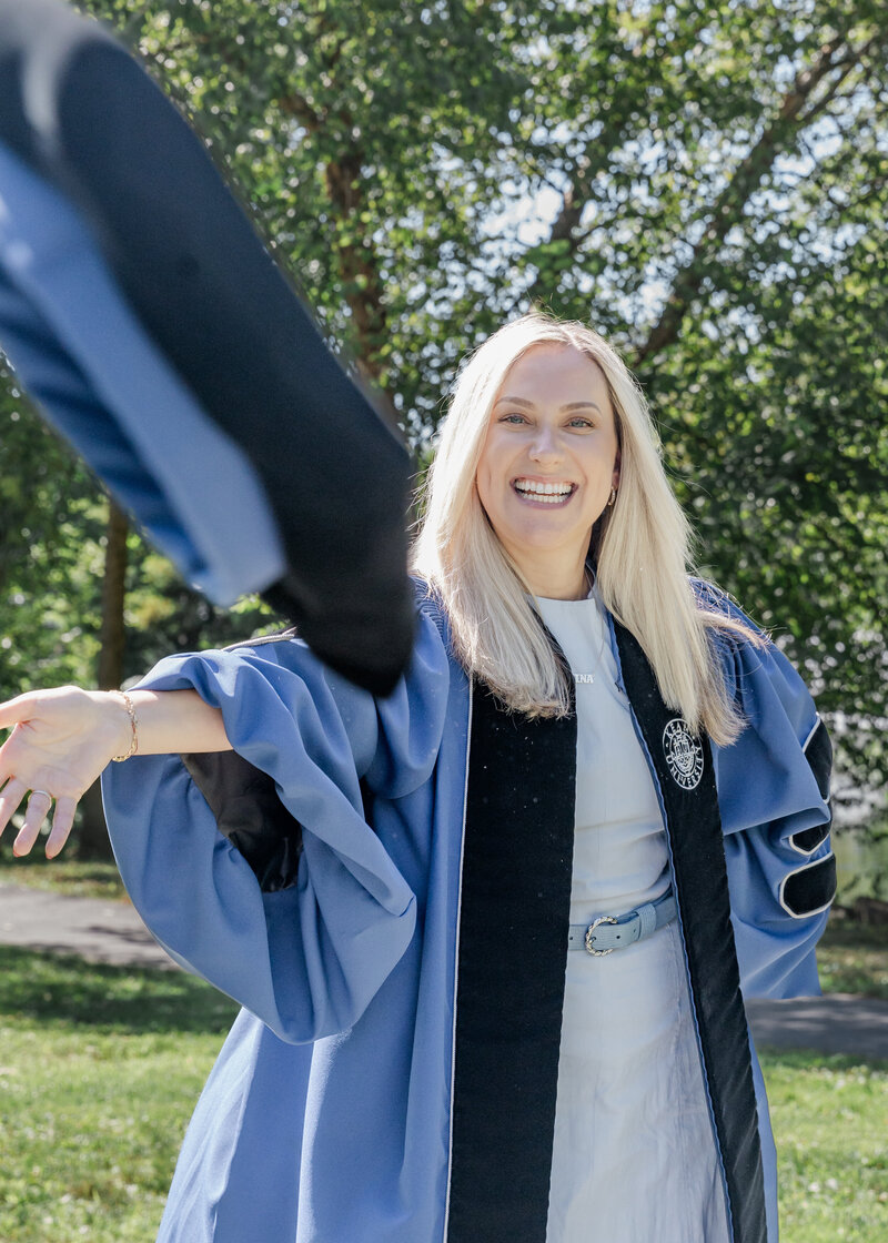 Lifestyle photo of a graduate wearing a graduation gown, throwing graduation hat at the camera.