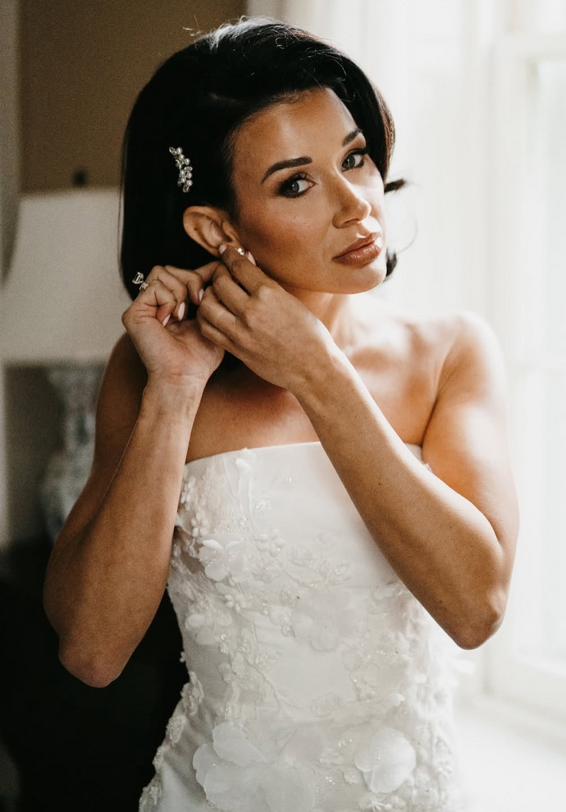 Bride putting in her earring before her wedding.