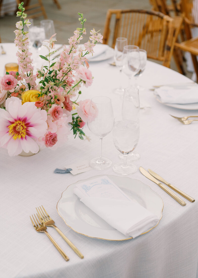 White wedding reception table with pink flowers and gold cutlery