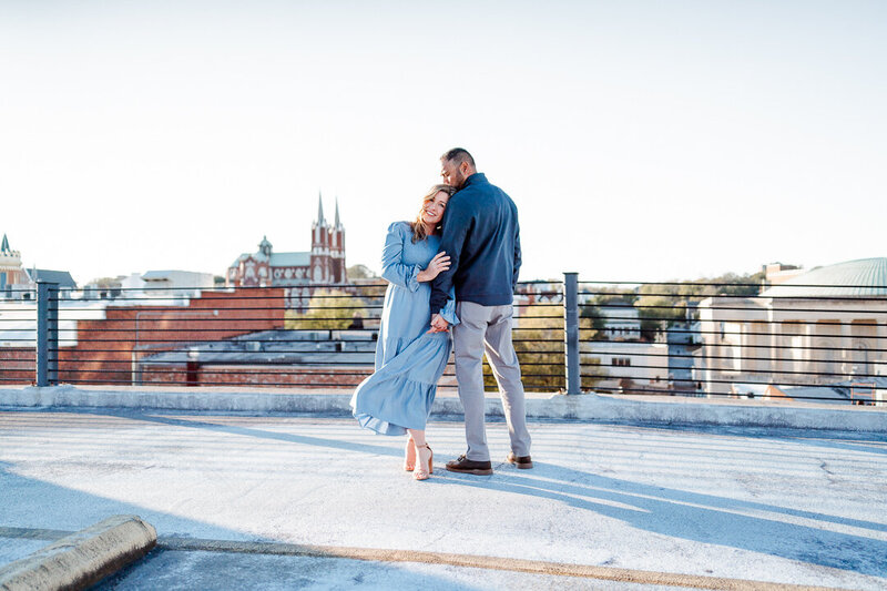 Couple holding hands on rooftop overlooking city at sunset
