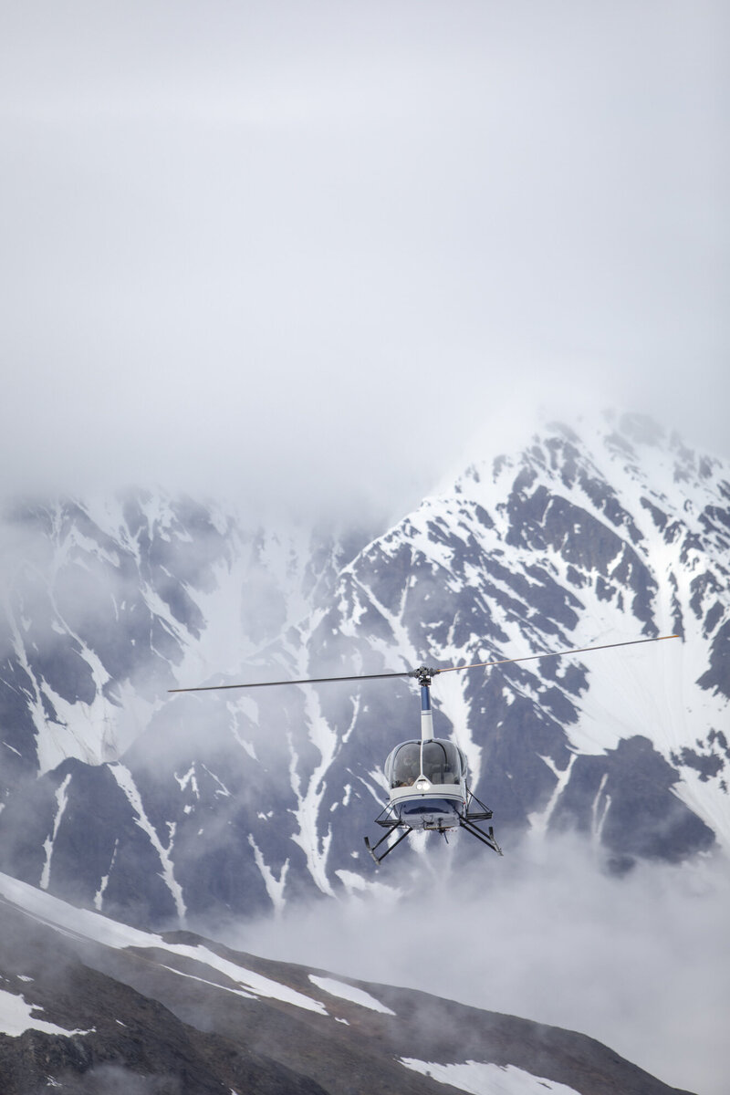Elopement Helicopter flying with big snowy peaks in the background.