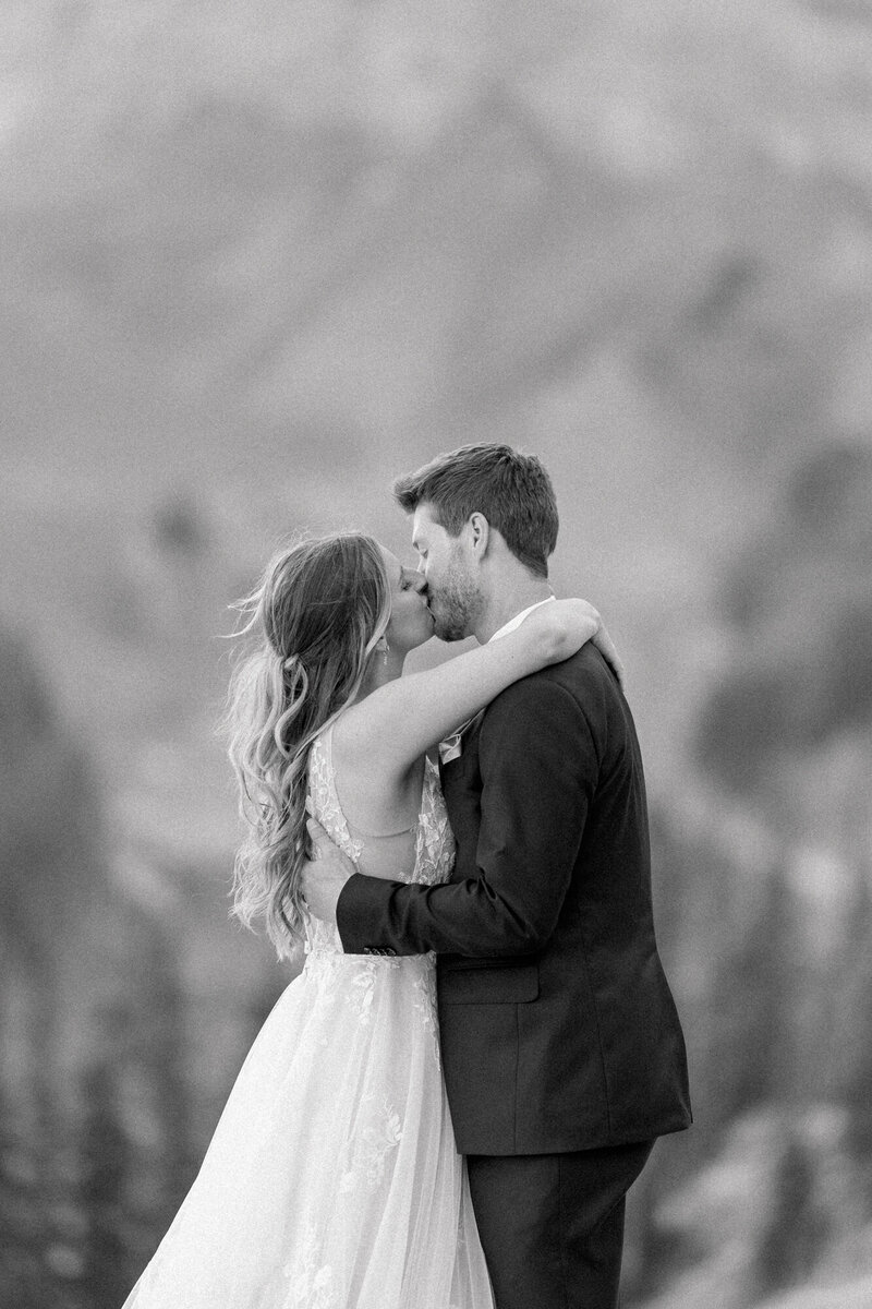 black and white image of a bride and groom kissing