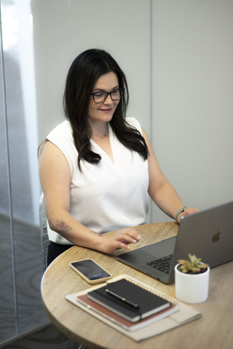 Luisa Kidwell smiling at laptop in white t-shirt – Career and Communication Coach at Kidwell Coaching and Consulting 4
