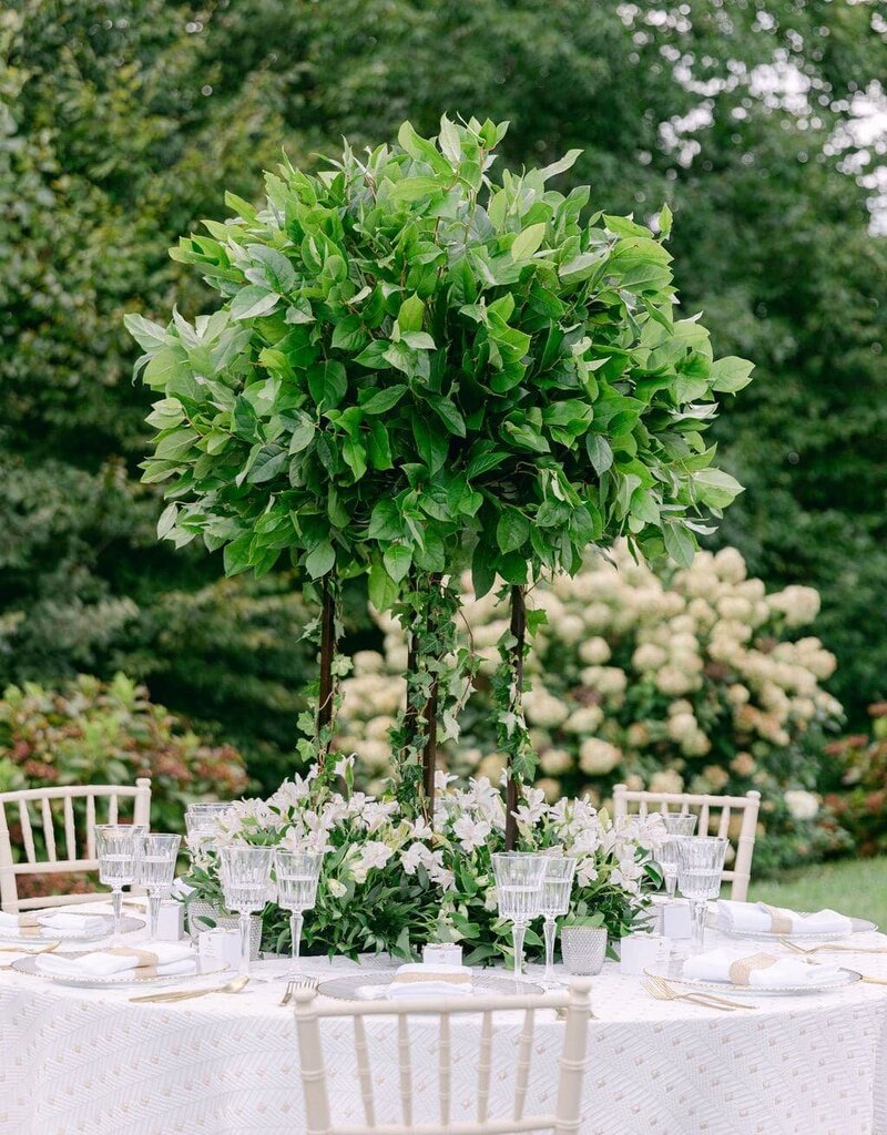 Elegant Charlottesville wedding reception table featuring tall greenery centerpiece and delicate white flowers, ideal for a vineyard or garden venue