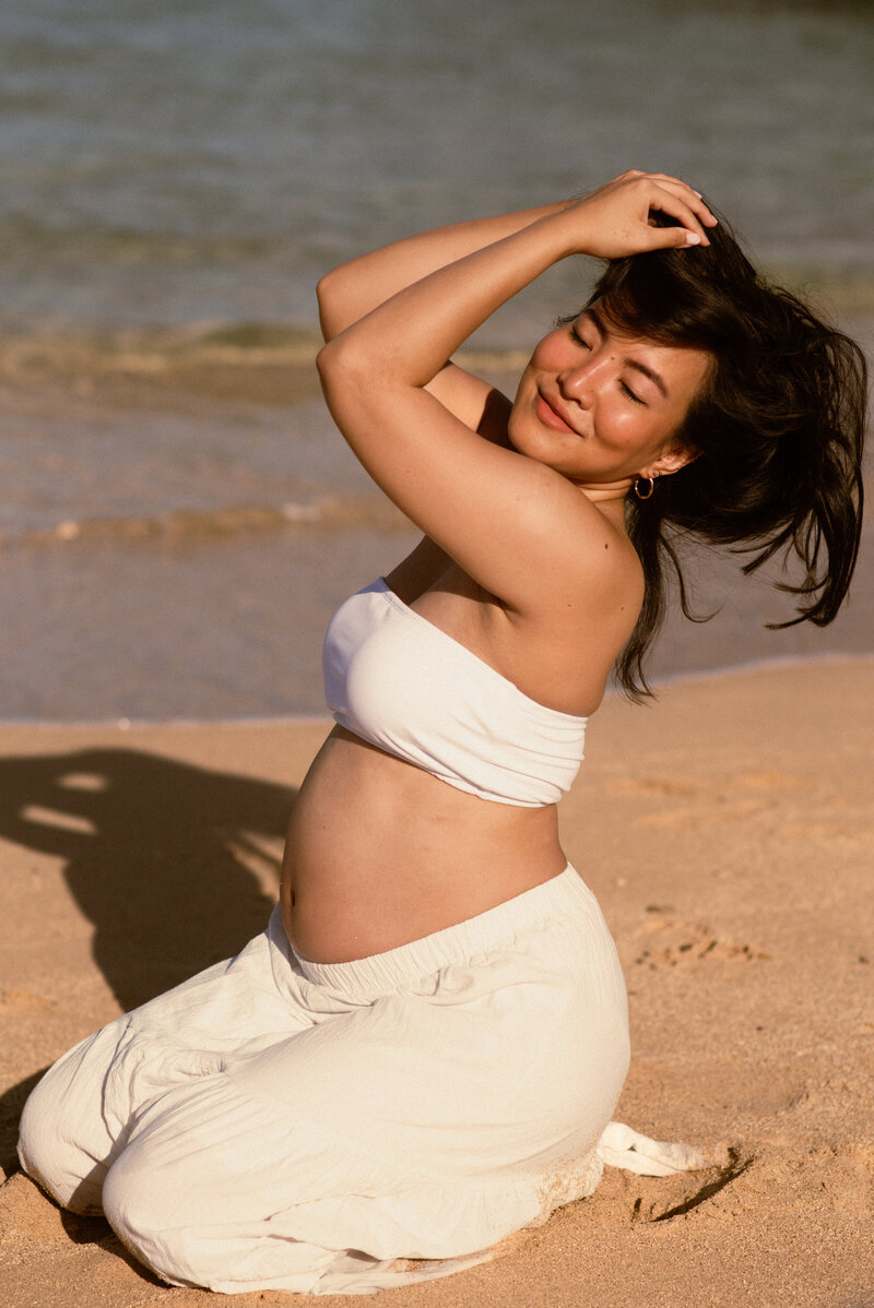 Woman posing on the beach for maternity portraits in Oahu, Hawaii